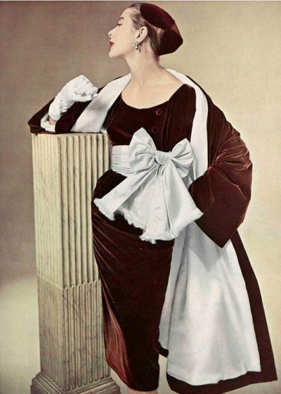 Bettina in chestnut velvet coat lined in double chiffon worn over velvet cocktail dress cinched in wide satin sash bow-tied, by Givenchy, photo by Pottier, 1952