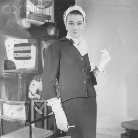 ca. 1954 --- Model wearing unfitted twill suit with unbuckled buckle at collar by Givenchy, white scarf, turban, and gloves. --- Image by © Condé Nast Archive/CORBISModel in Twill Suit by Givenchy, 1954　Henry Clarke